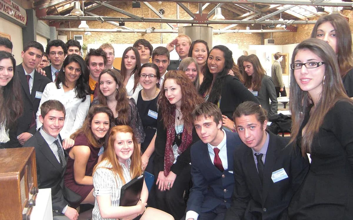 A large group of student delegates in formal clothes posing together at Athens Model United Nations
