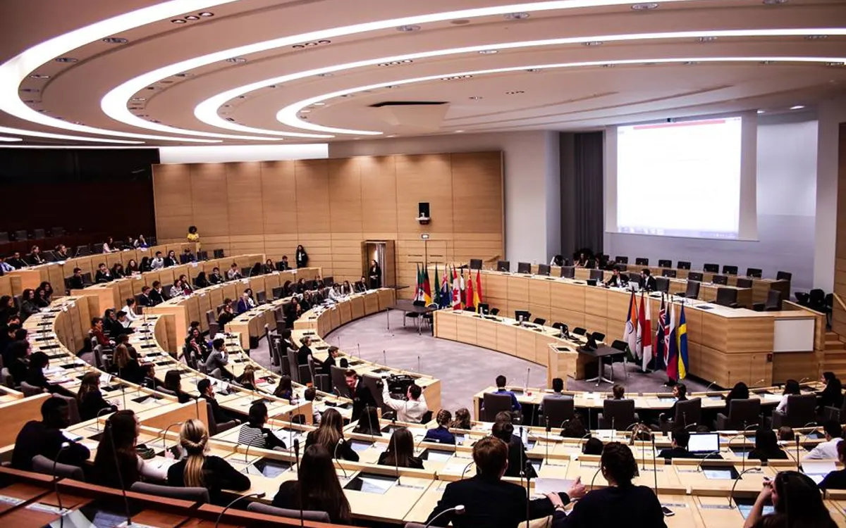 The General Assembly of International North Model United Nations meeting in a curved conference hall