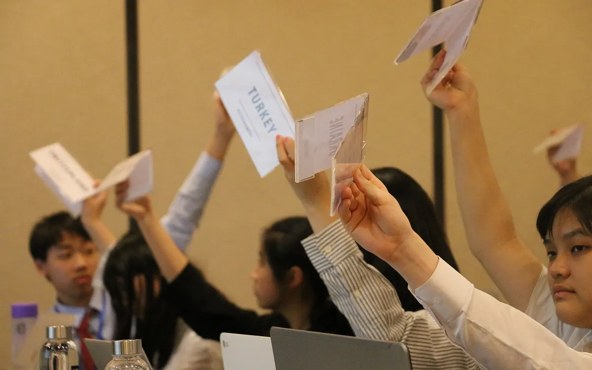 Delegates raising white country placards to vote in the Disarmament Committee of the Southern China International Model United Nations