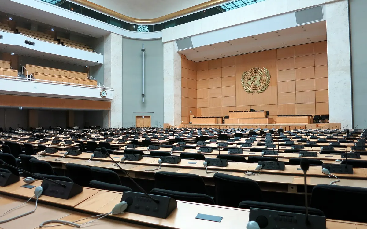 The Assembly Hall of the Palais des Nations in Geneva, seen from a delegate's desk, with long rows of desks facing the stage